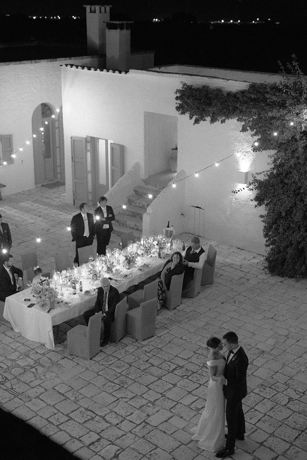 Black-and-white photograph of the couple dancing beside their wedding guests at Petrarolo