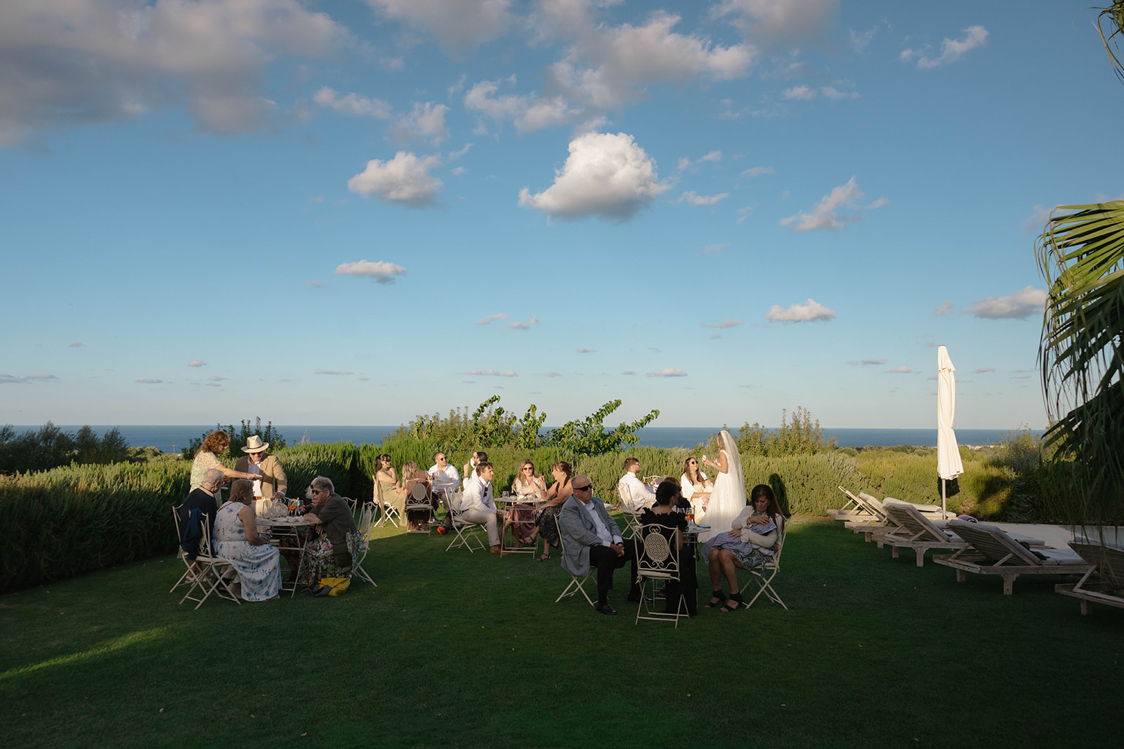Wedding guests enjoying drinks beside the pool with sea views
