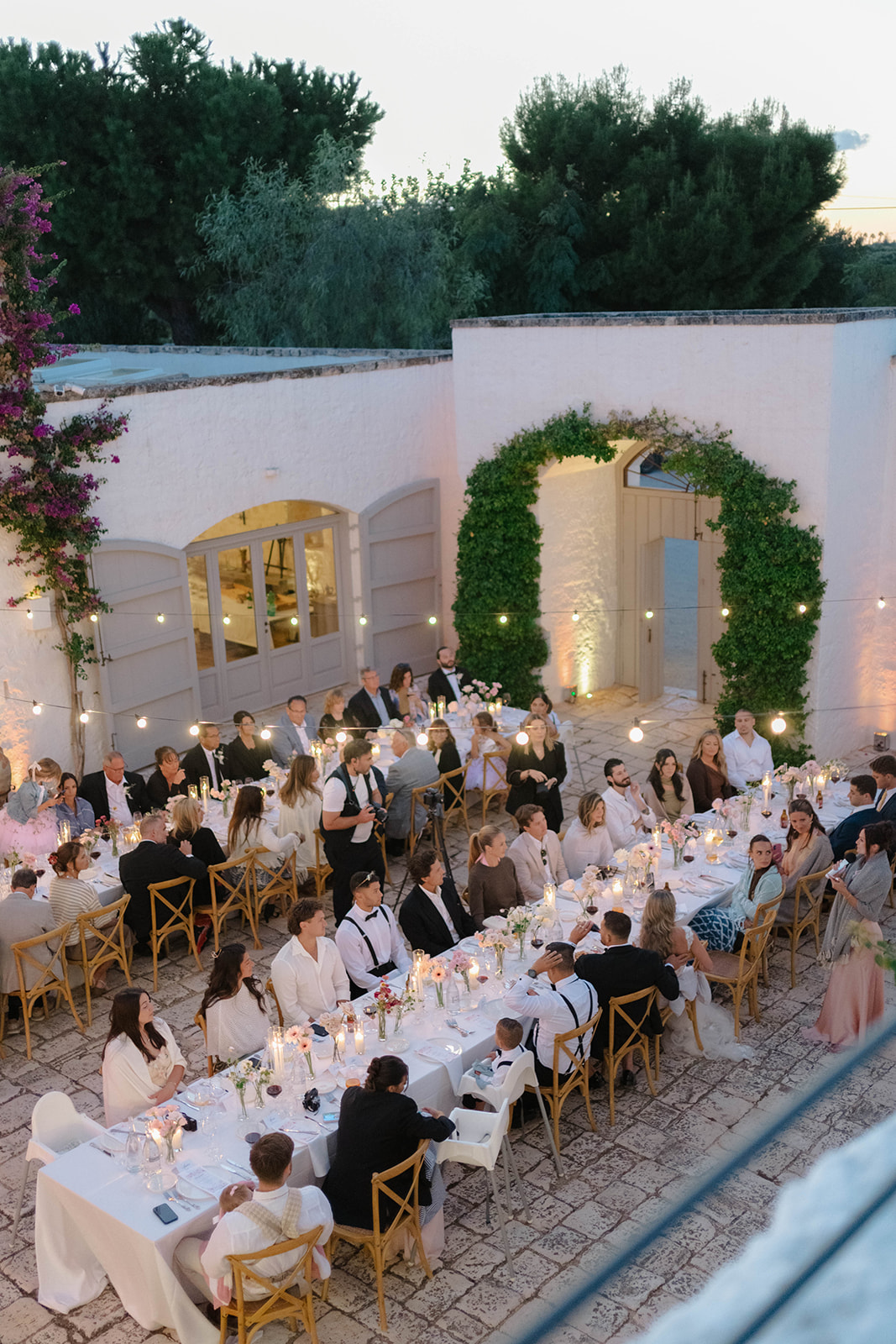 Wedding guests dining in the courtyard at dusk